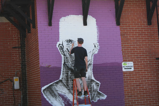 a person painting a mural on a brick wall